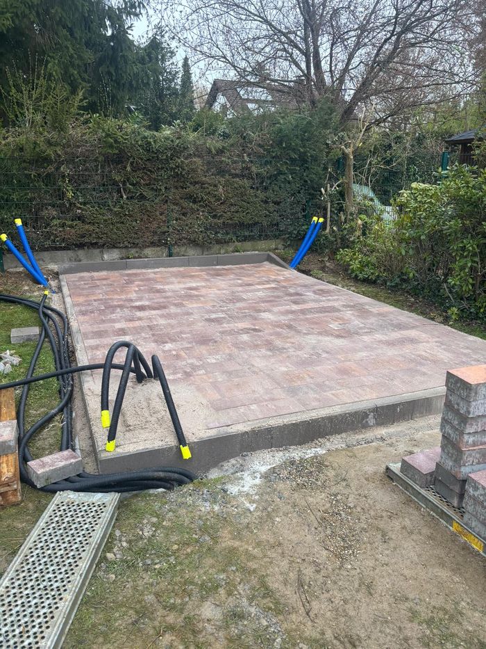 Neu verlegte Pflasterfläche im Garten mit Randsteinen und Leerrohren