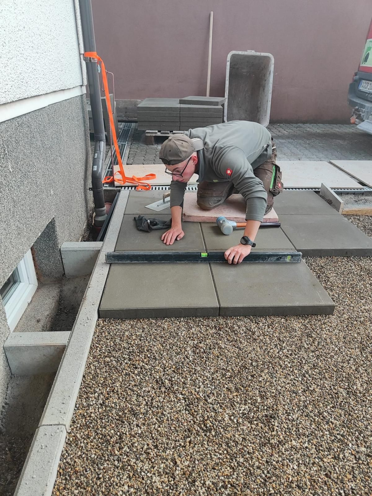 Landschaftsbauer verlegt Betonplatten und prüft sie mit der Wasserwaage